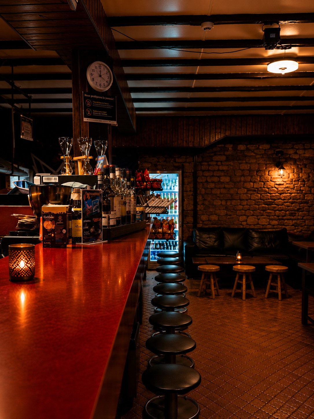 Le comptoir rouge du Bar Le Forgeron éclairé à la bougie