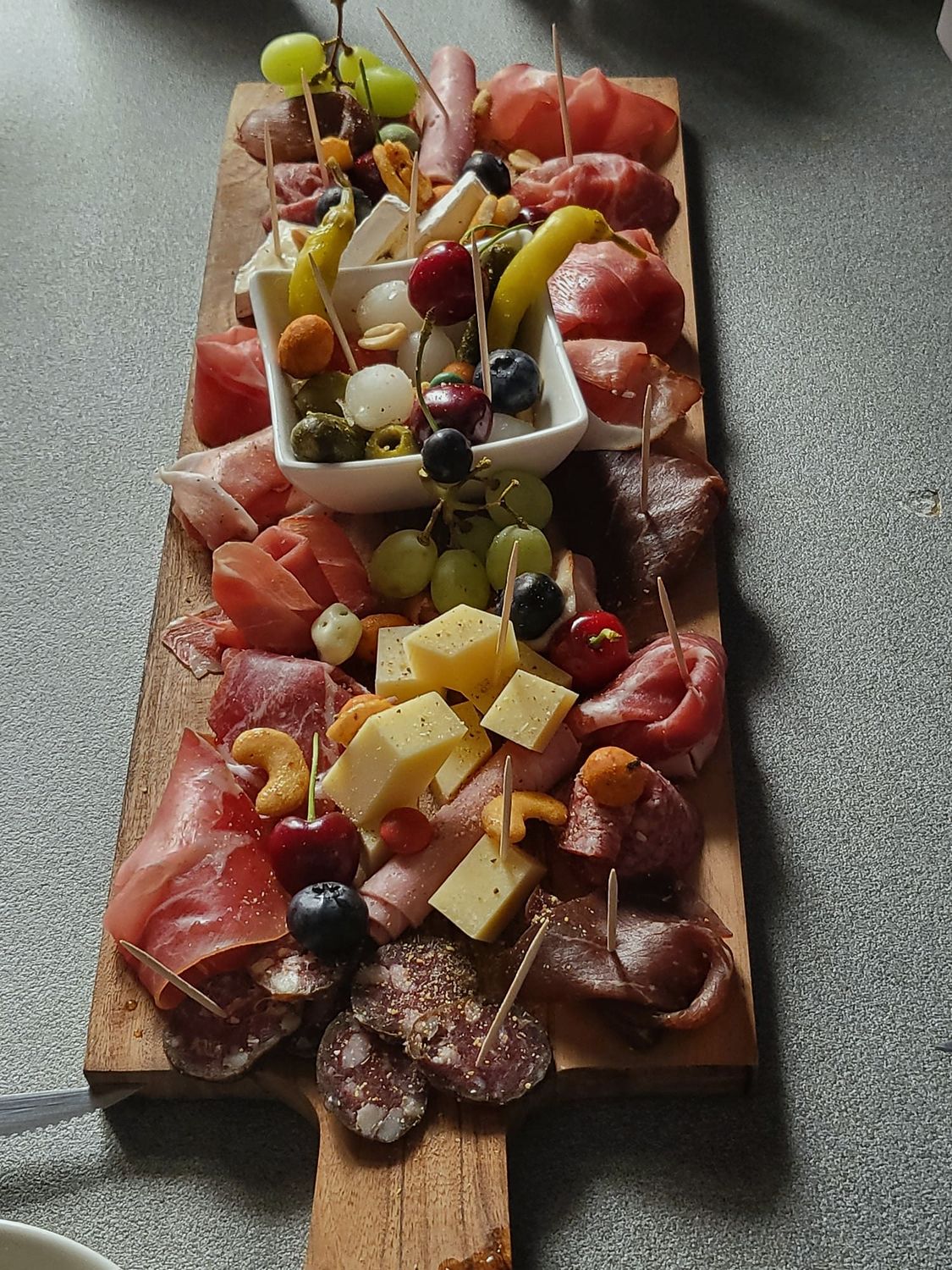 Grande planche de charcuterie suisse avec fromages, raisins, olives, cornichons