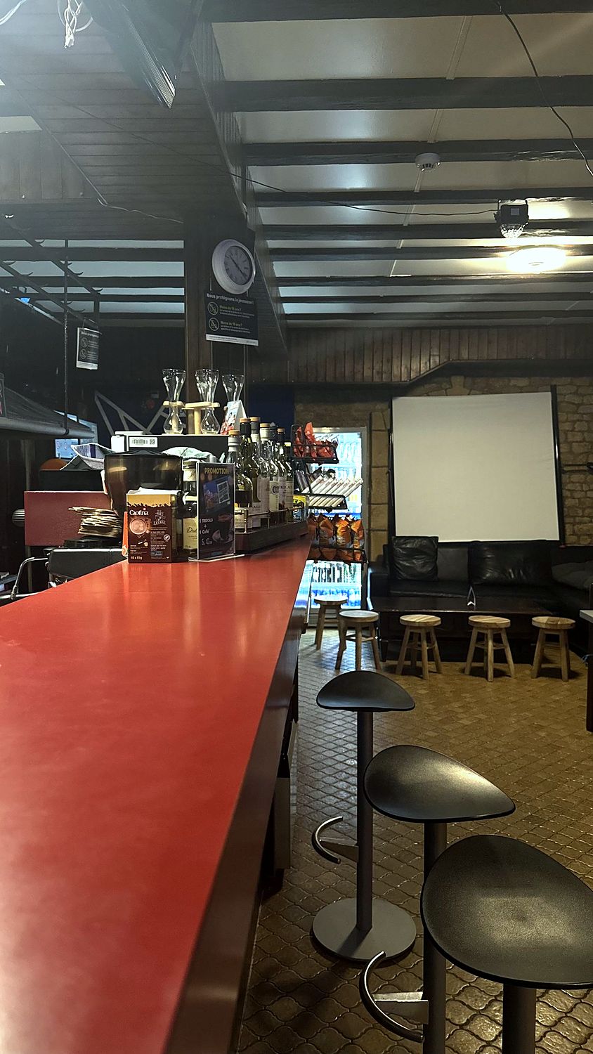 Vue en perspective du comptoir rouge avec tabourets et écran de projection