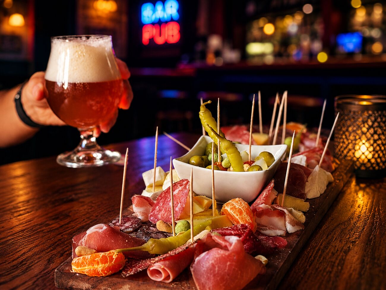 Planche de charcuterie et fromages, une bière levée pour trinquer